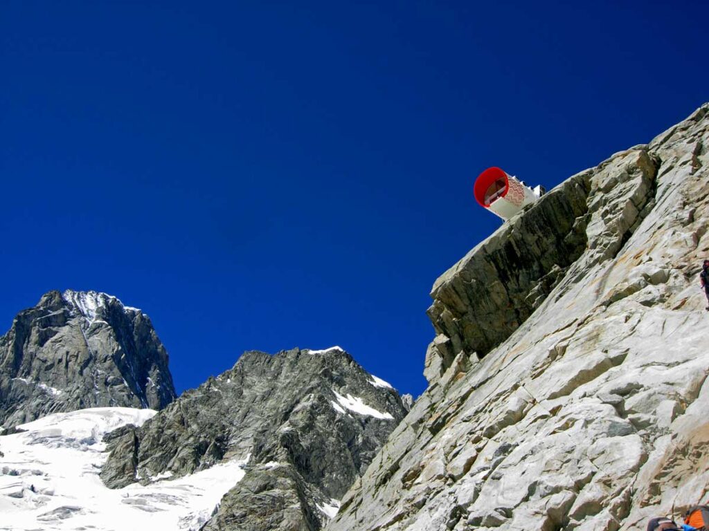 La fusoliera del Bivacco Gervasutti (2872 m) protesa nel vuoto, sullo sfondo delle Grandes Jorasses.